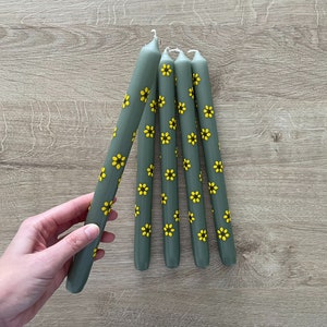 Handbeschilderde kaarsen. Bloemen geschilderde kaarsen. Groene dinerkaarsen met gele zonnebloemen. Gele zonnebloemen met een donkerbruine kern.