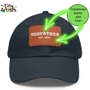 May include: A navy blue baseball cap with a brown leather patch that says "GODFATHER EST. 2023".