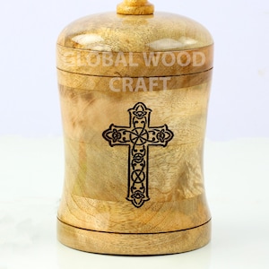 May include: A wooden jar with a lid, featuring a carved Celtic cross design. The jar is made of light brown wood and has the words "GLOBAL WOOD CRAFT" inscribed on the side.
