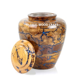 May include: A wooden cremation urn with a blue and brown marbled design. The lid is open and the urn is sitting on a white surface. The text "GLOBAL WOOD CRAFT" is printed on the side of the urn.