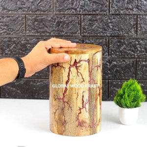 Könnte beinhalten: Ein Hocker aus Holz mit einem rosafarbenen Harzmuster. Der Hocker ist rund und hat eine natürliche Holzoptik. Das Harzmuster ist in Form von Blitzen. Der Hocker steht auf einer weißen Oberfläche. Der Text "GLOBAL WOOD CRAFT" ist auf dem Hocker sichtbar.