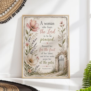 以下が含まれることがあります： 「A woman who fears the Lord is to be praised」のテキストと花のイラストが描かれた額入りのアートプリント。アートワークには門のイラストと聖書の詩篇31:30-31が含まれています。