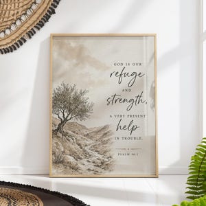 Può includere: Una stampa artistica da parete rettangolare in una cornice di legno chiaro con un'illustrazione paesaggistica color seppia di un ulivo su una collina rocciosa. Il testo recita: GOD IS OUR refuge AND strength, A VERY PRESENT help IN TROUBLE. PSALM 46:1.