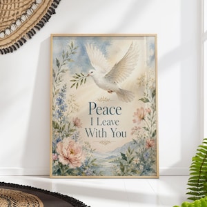 Puede incluir: Una impresión en acuarela enmarcada que presenta una paloma blanca que lleva una rama de olivo, sobre un cielo azul suave y un borde floral. El texto "Peace I Leave With You" se muestra en una escritura elegante.