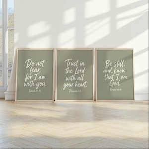 May include: Three sage green wall art prints in light wood frames. The first reads Do not fear, for I am with you. Isaiah 41:10. The second reads Trust in the Lord with all your heart. Proverbs 3:5. The third reads Be still, and know that I am God. Psalm 46:10.
