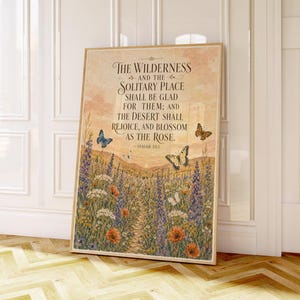 Può includere: Una stampa artistica da parete rettangolare che raffigura un paesaggio di fiori selvatici, farfalle e un sentiero sotto un cielo al tramonto. Il testo recita: THE WILDERNESS AND THE SOLITARY PLACE SHALL BE GLAD FOR THEM; AND THE DESERT SHALL REJOICE, AND BLOSSOM AS THE ROSE. — ISAIAH 35:1.