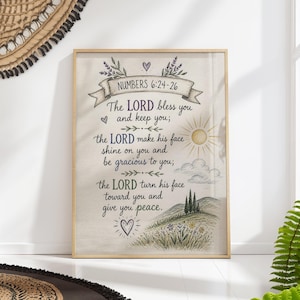 Op de afbeelding: Een ingelijste print met de tekst "Numbers 6:24-26" en een religieus citaat. Het kunstwerk toont een banner, zon, wolken en een landschap met bloemen. Het kleurenpalet omvat beige, paars en groen.