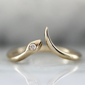 May include: A gold snake ring with a single diamond set in the head of the snake.