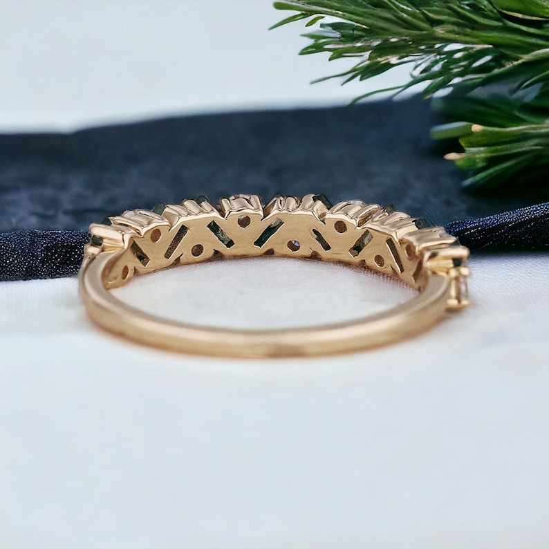 May include: A gold band ring with a row of small, clear gemstones set in a pave setting.