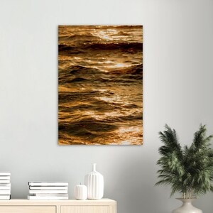 Peut inclure: Gros plan sur une eau qui ondule, reflétant la lumière dorée du soleil couchant. L'eau est d'une couleur brun foncé avec des reflets dorés et orange.