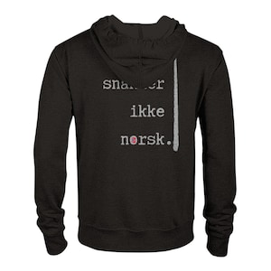 May include: Black hooded sweatshirt with the text "snakker ikke norsk." A vertical gray stripe is on the right side of the text. The word "norsk" has a small Norwegian flag graphic.