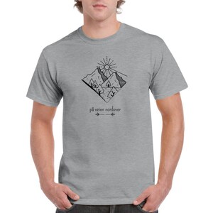 May include: A heather grey t-shirt with a black and white illustration of mountains, a sun, and trees. The text "på veien nordover" is printed below the illustration.