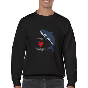 May include: Black sweatshirt featuring a blue and white orca whale design, a red heart with a blue cross, and the text "Jeg Norge!" in white. The sweatshirt is a casual garment.