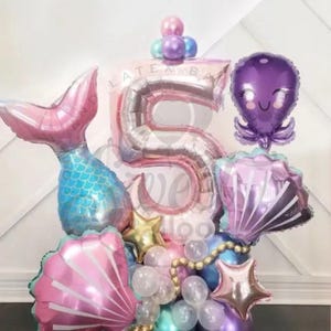 May include: A pink and silver number 5 balloon with a mermaid tail, seashells, an octopus, and stars. The balloons are arranged in a bouquet.