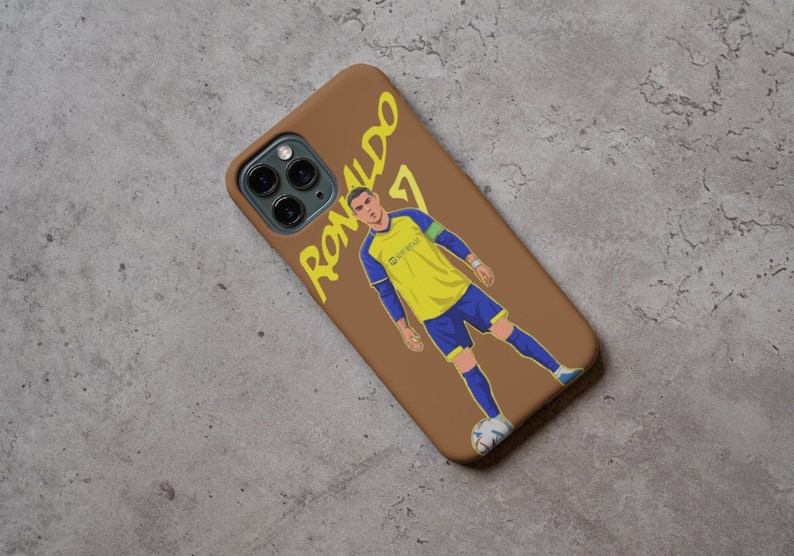 Puede incluir: Una funda de tel&eacute;fono marr&oacute;n con una ilustraci&oacute;n amarilla y azul de un jugador de f&uacute;tbol con el texto "Ronaldo 7" en la funda.