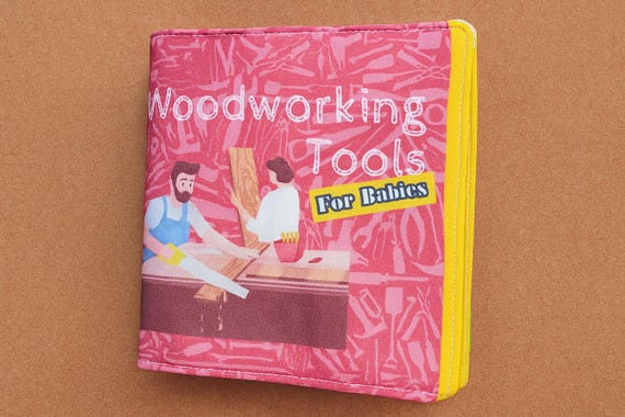 A soft fabric baby book shaped and styled like a woodworking manual — a genuinely clever, handmade gift that bridges dad's hobby and baby's world.