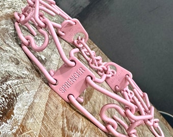 Puede incluir: Cadena de entrenamiento para perros de metal rosa con la palabra "SPRENGER" grabada en una etiqueta de metal.