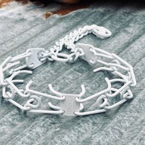 Puede incluir: Collar de púas de metal blanco para perros. El collar está hecho de púas de metal unidas y tiene una cadena unida a él. El collar está etiquetado como "SPRINGER".