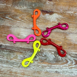 May include: Five colorful metal snap hooks in a starburst pattern. The hooks are red, pink, yellow, orange, and purple.