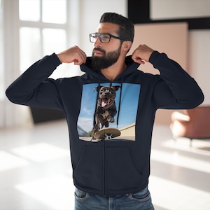 Pode incluir: Um moletom azul marinho com zíper e um estampado gráfico de um cão preto andando de skate. O cão está usando uma coleira e está sorrindo.