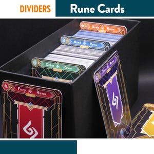 Pode incluir: Uma caixa preta cheia de Cartas de Runas, com divisórias rotuladas "Calm Rune", "Mind Rune", "Body Rune" e "Fury Rune". As cartas têm um design dourado e vermelho com um símbolo branco.