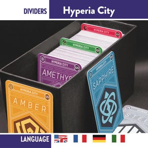Pode incluir: Uma caixa preta para guardar cartas com divisórias com a inscrição "Hyperia City". As divisórias são de várias cores, incluindo vermelho, verde e roxo, com nomes de cartas como "Amber" e "Sapphire". A caixa está cheia de cartas colecionáveis.