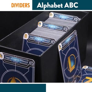 Pode incluir: Caixa preta de armazenamento de cartas com divisórias rotuladas com letras do alfabeto. As divisórias são para cartas League of Legends Riftbound. As cartas têm um design azul e dourado. O texto "DIVIDERS Alphabet ABC" está no topo.