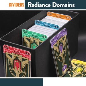 Pode incluir: Uma caixa de armazenamento preta contendo várias cartas de jogo com o texto Radiance e RAD. As cartas apresentam abas superiores coloridas em vermelho, verde, azul, laranja e roxo, com padrões geométricos dourados e verde-escuros.