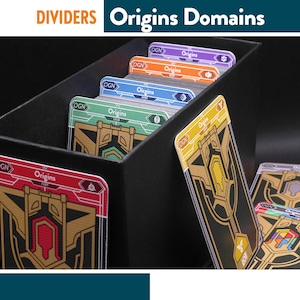 Puede incluir: Caja negra que contiene divisores de Dominios de Orígenes coloridos. Cada divisor presenta una combinación de colores y un diseño únicos, con los textos "Origins" y "OGN" visibles. Los divisores están diseñados para organizar cartas.