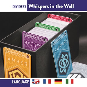 Pode incluir: Uma caixa preta para guardar cartas com divisórias para o jogo de cartas "Whispers in the Well". As divisórias estão rotuladas como "Amber", "Amethyst", "Sapphire" e "Steel". A caixa e as divisórias têm um design geométrico com o título do jogo e a palavra "Dividers" no topo.