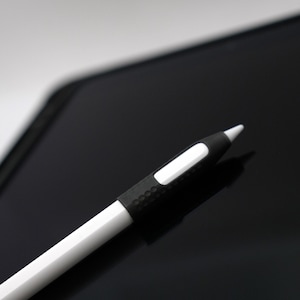 May include: A black and white stylus with a white tip, lying on a black surface.