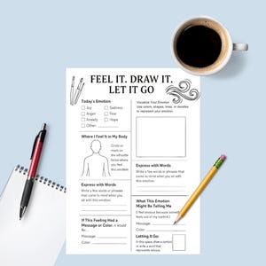 May include: A white worksheet with the text "FEEL IT. DRAW IT. LET IT GO" and sections for emotional expression. A cup of coffee, a red and black pen, a yellow pencil, and a notepad are on a blue surface.