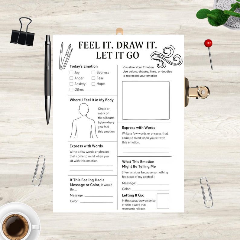 May include: A white paper with the text "FEEL IT. DRAW IT. LET IT GO" and prompts to explore emotions. Includes sections for identifying emotions, body sensations, and expressive drawing. A black pen, binder clip, and paper clips are also visible.