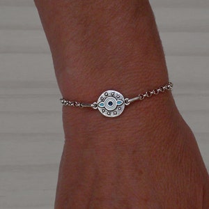 Op de afbeelding: Zilveren kettingarmband met een ronde bedel met een blauw boze oog ontwerp.