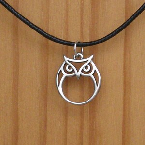 Op de afbeelding: Een zilveren uil hanger ketting met een zwart leren koord.