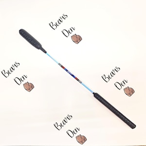 Könnte beinhalten: Eine schwarze und blaue Angelrute mit einem schwarzen Griff und einer blauen Schnur. Die Rute ist mit roten, weißen und blauen Streifen verziert. Die Rute ist auf dem Bild mit "Bears Den" beschriftet.