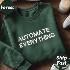 Op de afbeelding: Een bosgroene sweater met ronde hals en de wit geborduurde tekst "AUTOMATE EVERYTHING" in het midden op de borst. Het kledingstuk heeft lange mouwen, een geribbelde kraag en geribbelde boorden voor een strak en eenvoudig ontwerp.