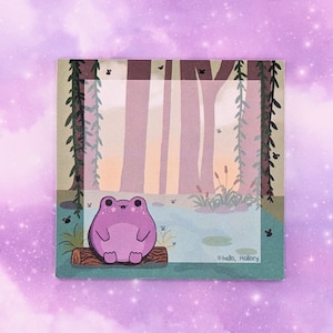 May include: A square sticky note featuring a purple frog sitting on a brown log in a pond. The background shows a forest with tall trees, hanging vines, and small flying insects. The text "hello, Hollory" is printed in the bottom right corner.