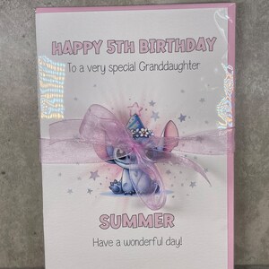 May include: A pink birthday card with a blue cartoon character wearing a party hat. The card says "Happy 5th Birthday" and "To a very special Granddaughter". The character's name is "Summer" and the card says "Have a wonderful day!"