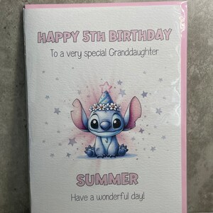 May include: A pink and white birthday card with a blue cartoon character wearing a party hat. The card says "Happy 5th Birthday" and "To a very special Granddaughter" and "Summer" and "Have a wonderful day!"