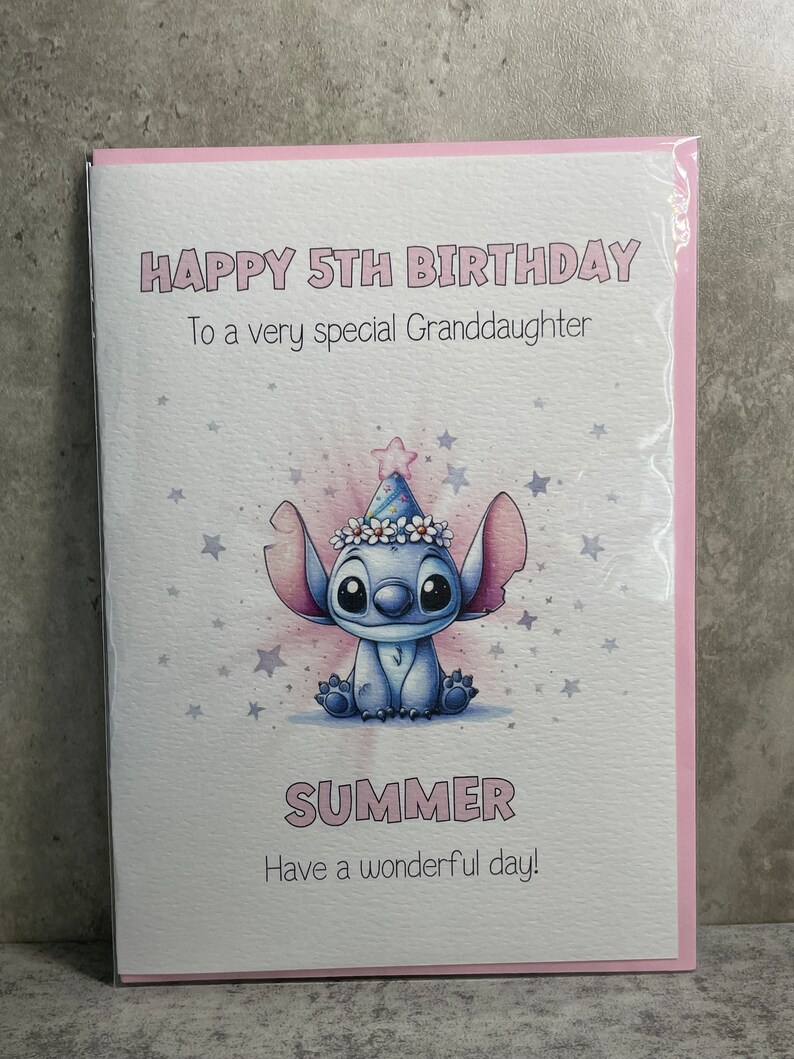 May include: A pink and white birthday card with a blue cartoon character wearing a party hat. The card says "Happy 5th Birthday" and "To a very special Granddaughter" and "Summer" and "Have a wonderful day!"