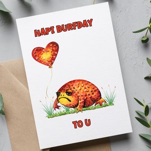 May include: A white card with the text "HAPI BURFDAY TO U" in red and black lettering. A red heart balloon is floating above a cartoon red and orange frog with yellow eyes.