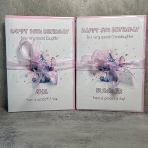 May include: Two pink birthday cards with a blue cartoon character wearing a party hat. The card on the left says "Happy 10th Birthday To a very special Daughter Ava Have a wonderful day!" The card on the right says "Happy 5th Birthday To a very special Granddaughter Summer Have a wonderful day!"