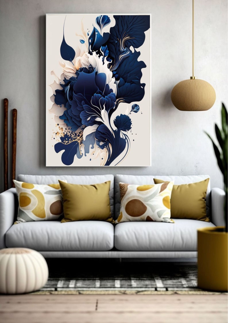 May include: Abstract art print featuring a blue and white floral design with gold accents. The print is framed and hanging on a white wall above a gray couch with yellow and brown pillows.