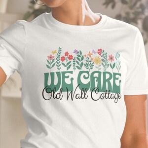 May include: White t-shirt with a green floral design and the text "WE CARE Old Wall Cottage".