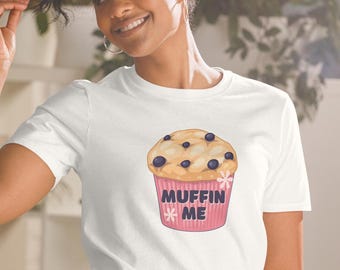 Könnte beinhalten: Weißes T-Shirt mit einem pinkfarbenen und gelben Cartoon-Blaubeermuffin mit dem Text "Muffin Me" darauf.