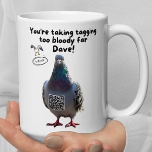 Op de afbeelding: Witte keramische mok met een duif en een QR-code. De mok heeft de tekst "You're taking tagging too bloody far Dave!" en een kleine cartoonvogel met het woord "HAHA".