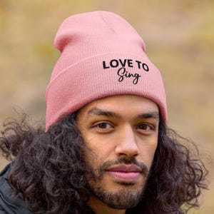 May include: A pink beanie with the text "LOVE TO Sing" in black lettering.