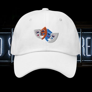 May include: White baseball cap with an embroidered design of three colorful theatrical masks. The masks are orange, blue, and white.