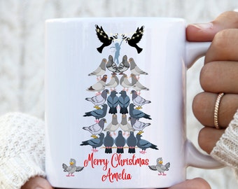 May include: White ceramic mug featuring a Christmas tree design made of pigeons. The design includes the text "Merry Christmas Amelia" in red script. Two cartoon pigeons are on the bottom of the mug.